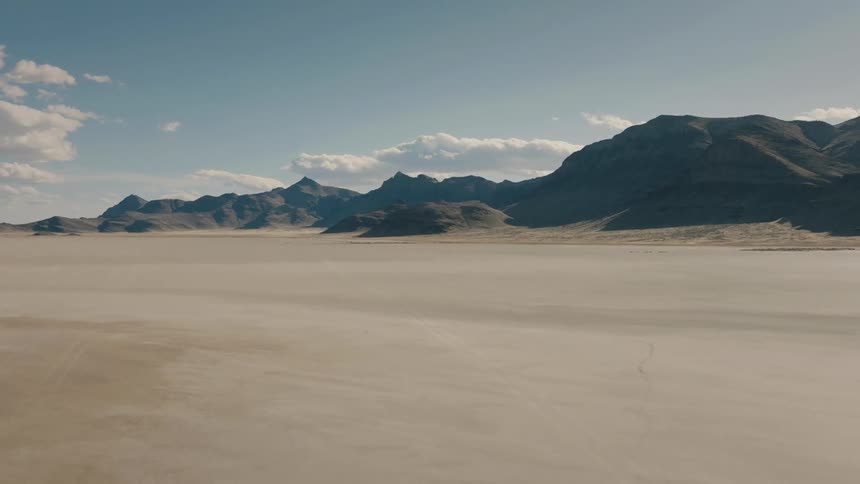 Tall sand dunes form behind a vast desert