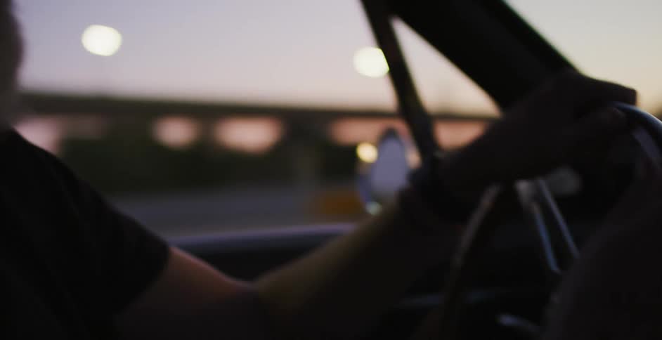 A man drives a vehicle on a highway at dawn or dusk