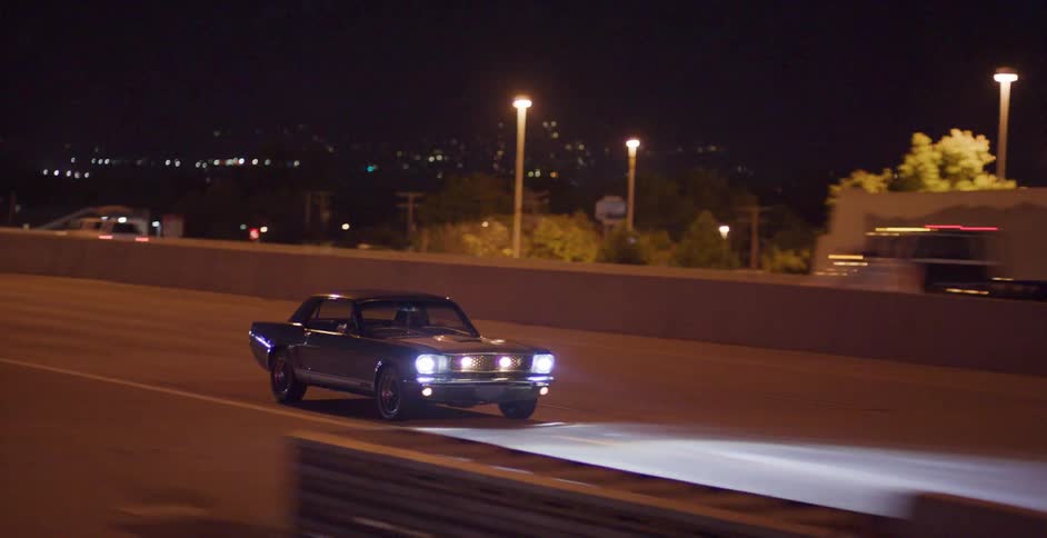 A car travels on an empty highway away from the city at night