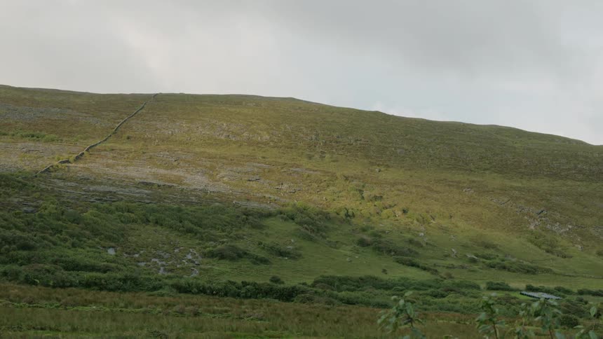 View of a barren hill on a cloudy day