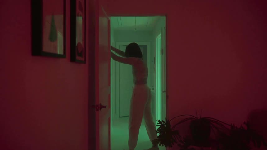 A white woman leans against the wall in a hallway in a house