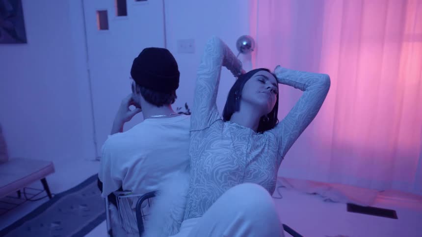 Man and woman sit in the chairs in the blue lit room
