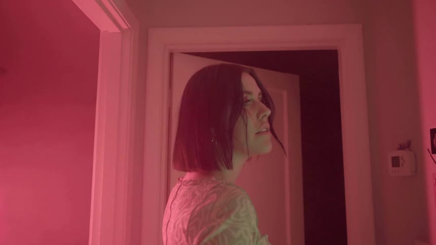 A teenager stands in a hall with flashing red lights
