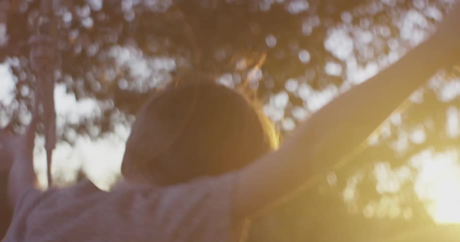 A boy runs and jumps on a swing as the sun sets