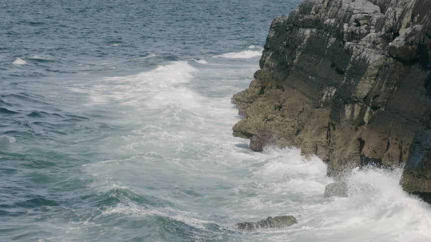 Ocean waves crash against the high cliff rocks