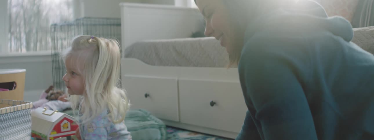 A teenage girls plays with a younger girl on the floor