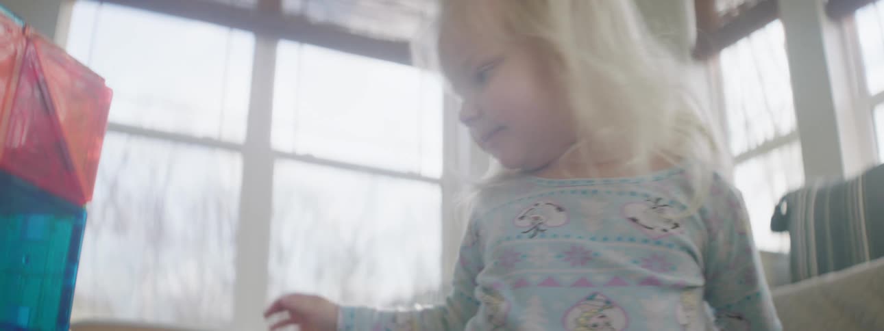 Blonde toddler girl plays in the living room at home