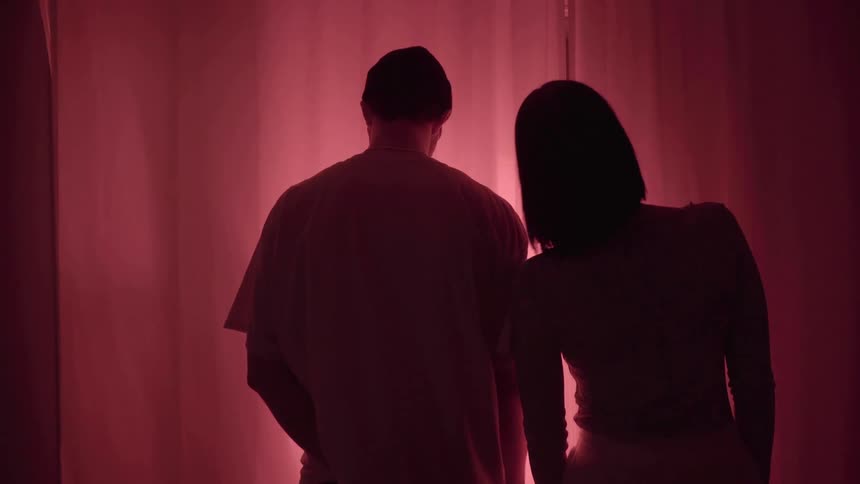A man and woman are standing together by a curtain