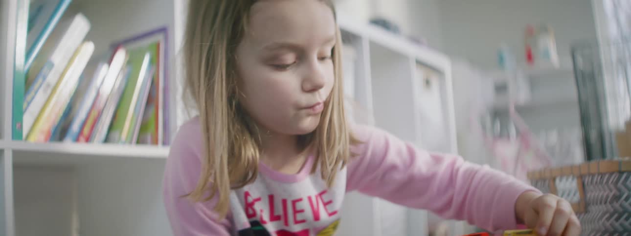 A young girl plays with stacking bricks in her playroom at home