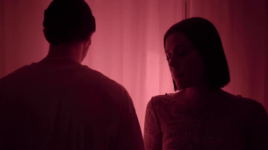 A man and a woman stand in a dark room