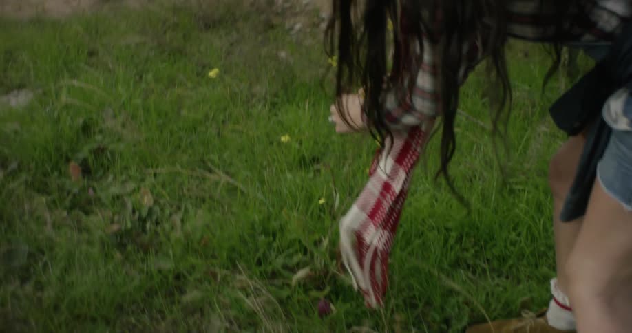 Girl in red knitted cap stops to pick flowers
