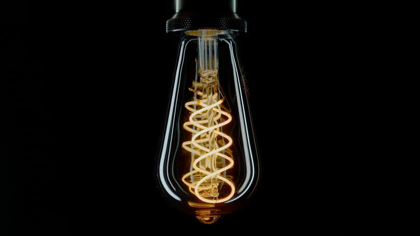 A light bulb fixture is turned on and the filament glows before fading