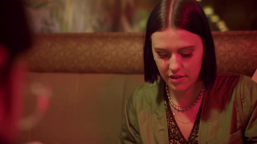 A woman talks to her friend as they have dinner in a restaurant booth