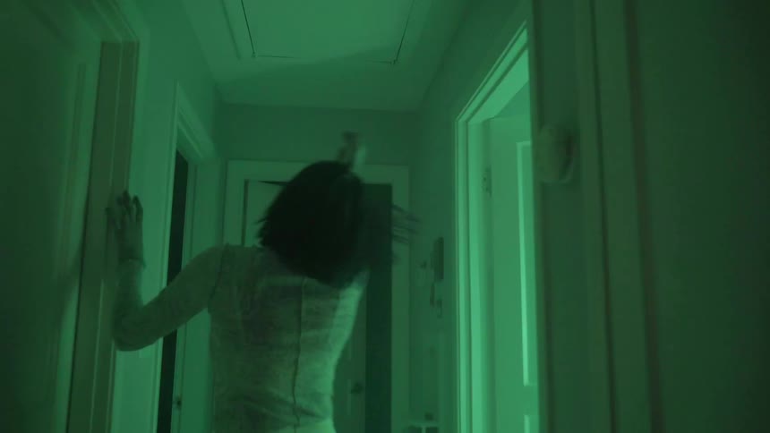 A teenager stumbles and spins around in a hallway as lights flash