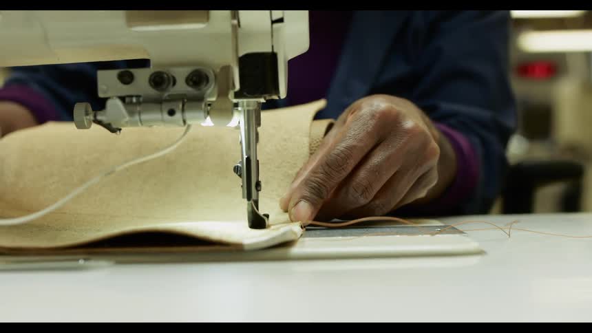 A person holding a fabric underneath a sewing machine