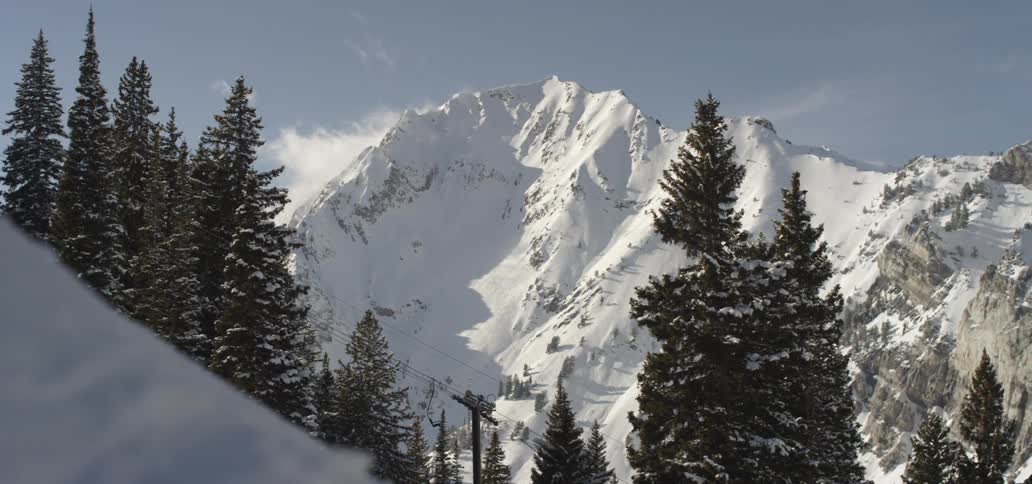 A ski lift sits empty in front of a snow covered mountain