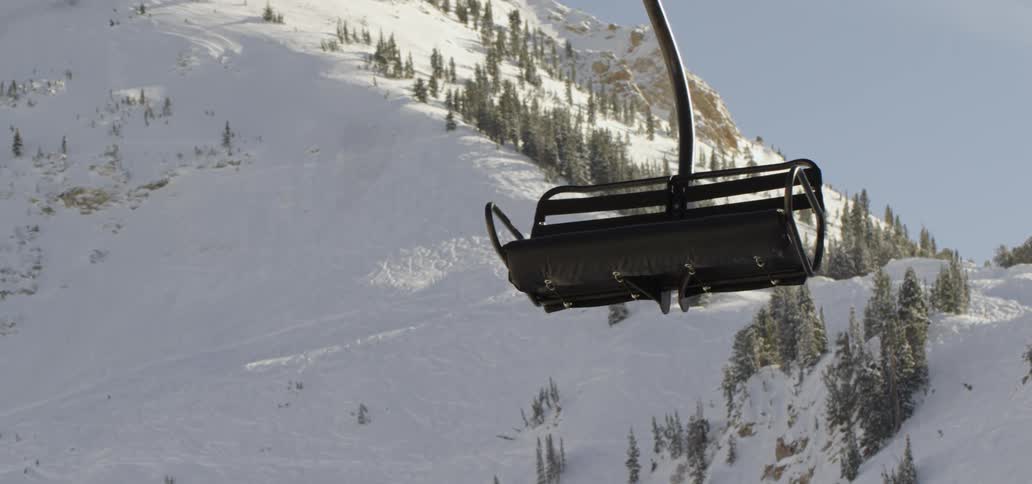 A ski lift with a snow covered mountain in the background