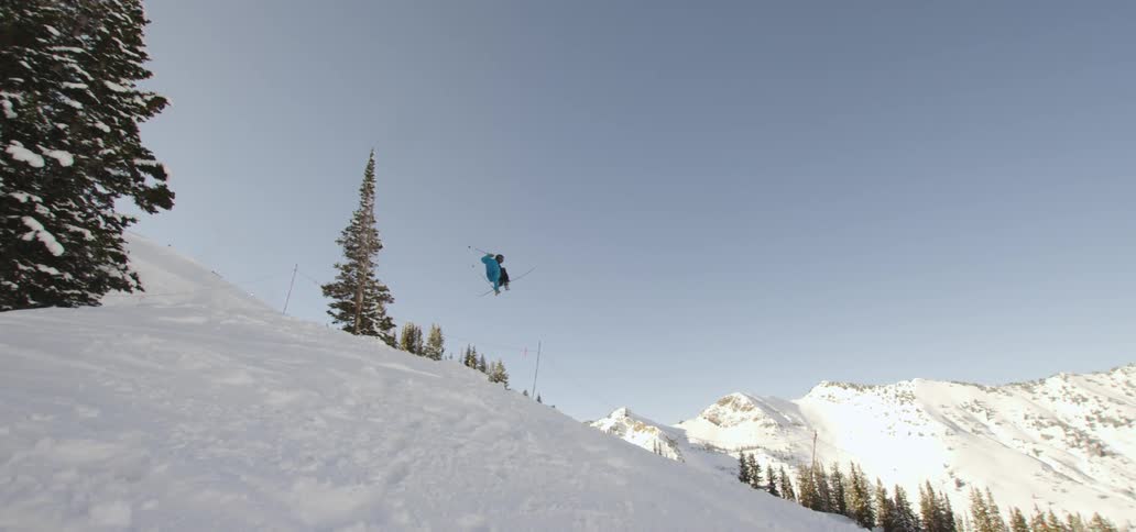 A skier does tricks off a ramp at a ski slope in the mountains
