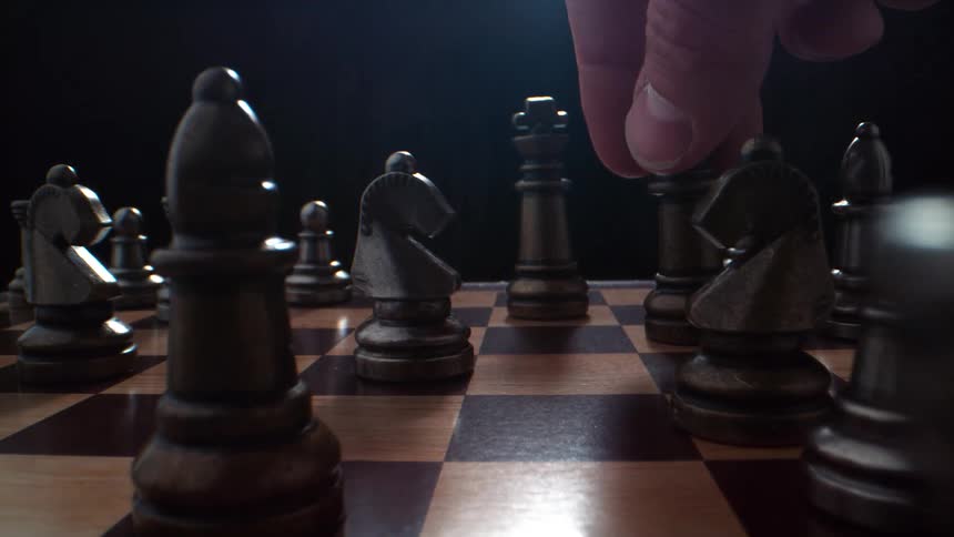 A person moves the chess piece on the board
