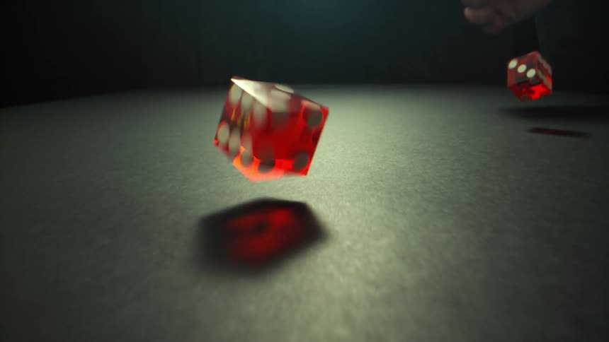 A man rolls a pair of dice on a black table
