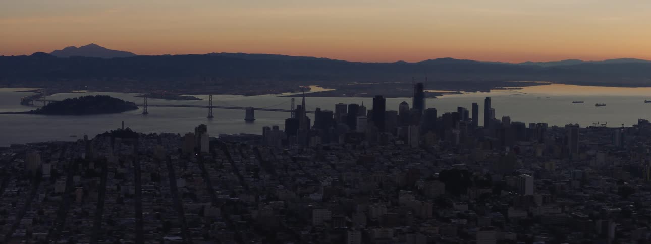 The sun is setting in the horizon near a downtown area