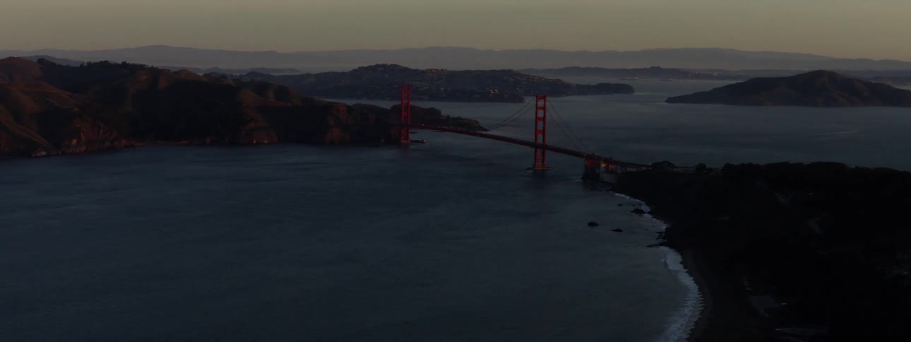 A red suspension bridge spans a body of water
