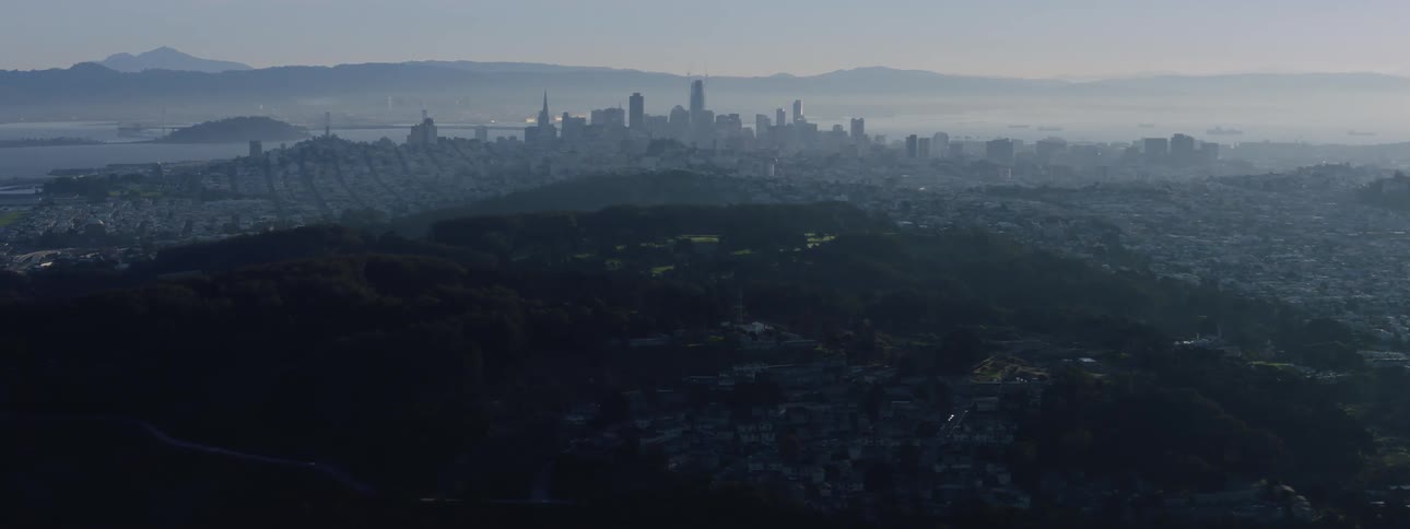 Fog sets over a city filled with dense neighborhoods and a downtown that sits next to the ocean and across from mountains
