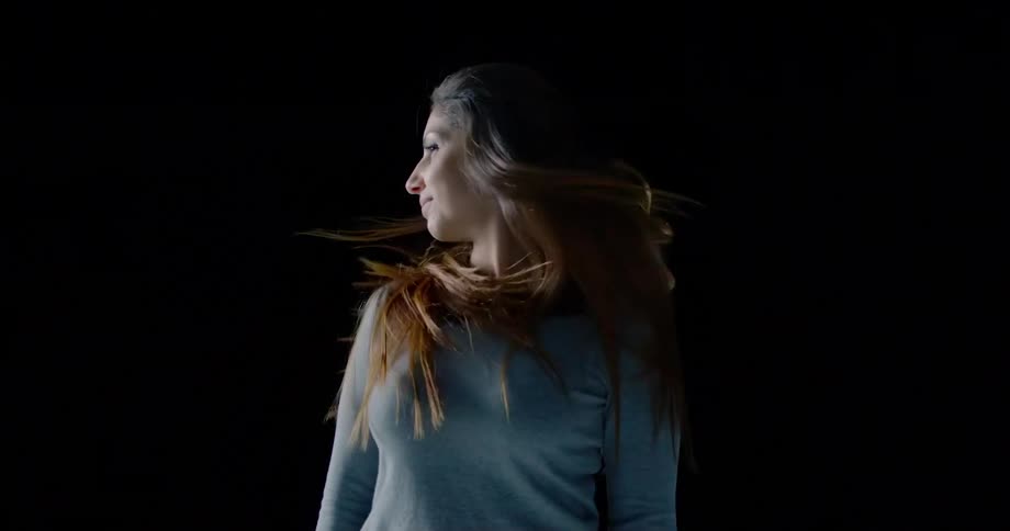 Woman turns her head from left to right in black background