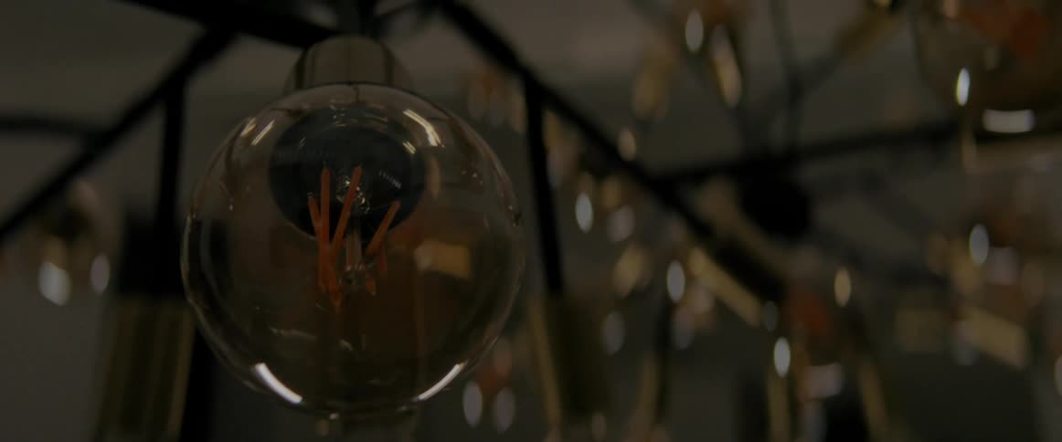 A chandelier is turned off and on with one bulb front and center