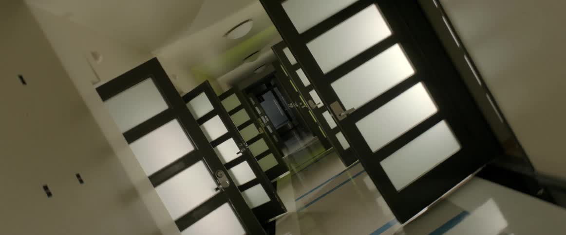 A corridor with open doors on both sides and flashing colorful lights