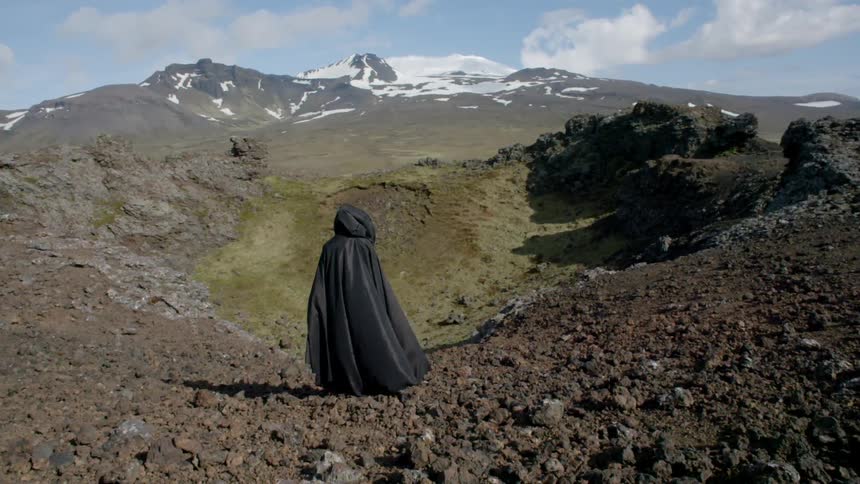 A person wearing black robes is standing on a mountain