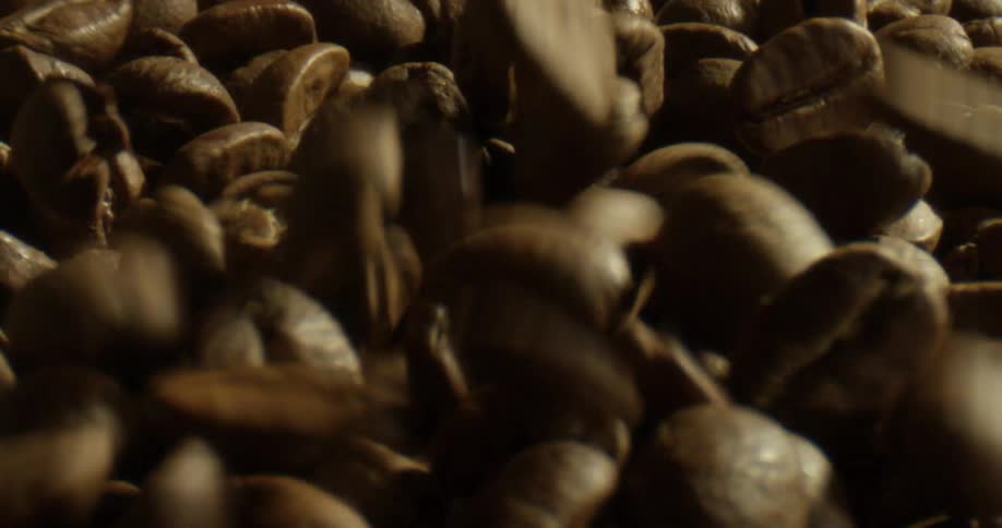 Close up of roasted coffee beans falling on to the beans