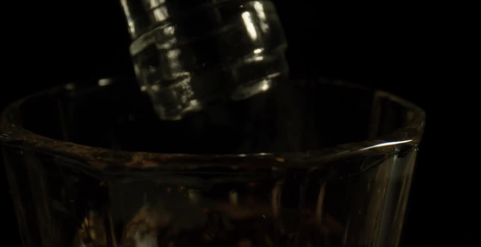 A bottle resting on a cocktail glass