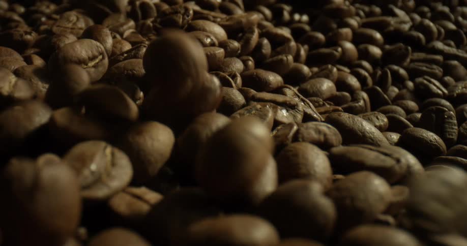 Coffee beans drop onto a pile of more beans