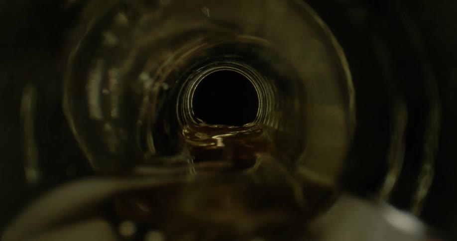 Liquid pours out of a glass beer bottle on its side