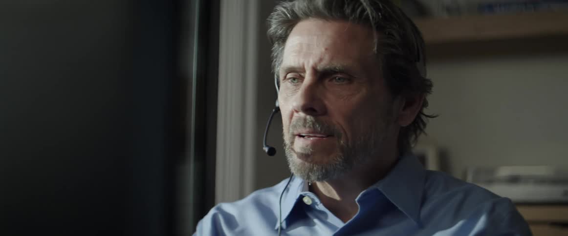 An elderly white man puts on a headset and begins speaking to someone