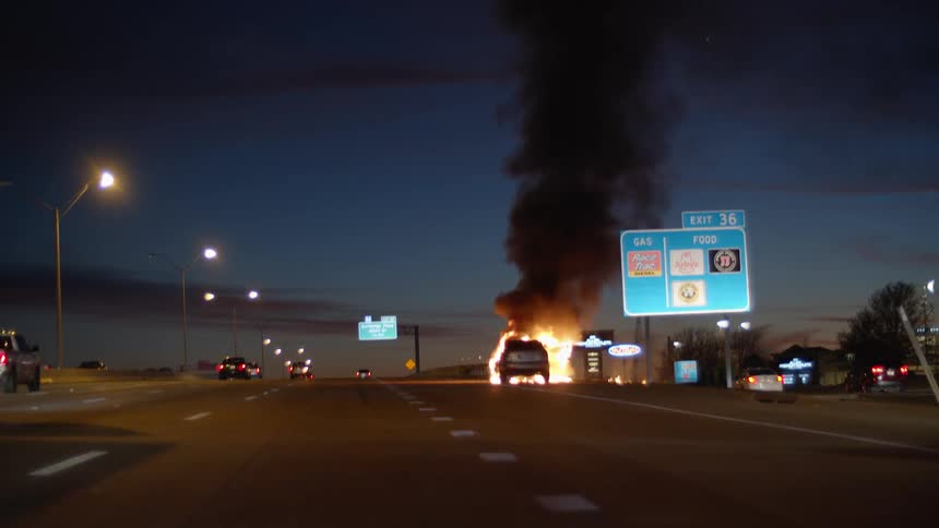 A vehicle is pulled off to the side of the highway engulfed in flames