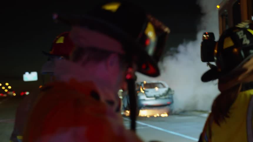 A group of fireman work outside to put out a vehicle fire