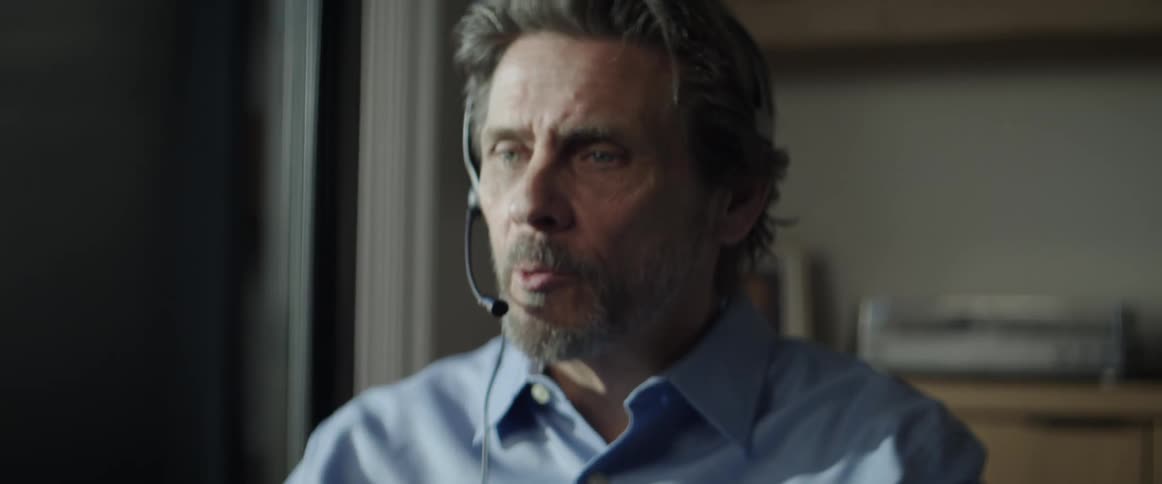 A man wears a headset and talks as he types on his keyboard