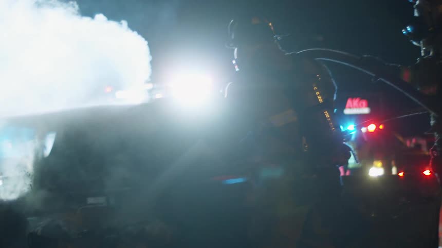 Firefighters try to extinguish a crashed automobile that caught fire