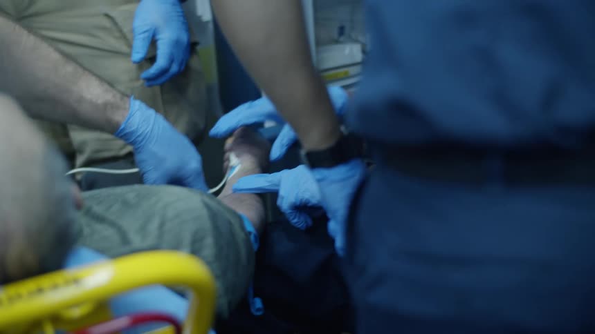 A man lies on a stretcher as ems work on him