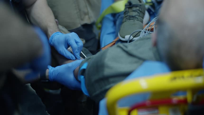A man lies on a gurney as paramedics work on him