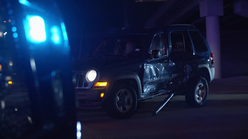 Lights flash from an ambulance after a jeep gets into a wreck at night