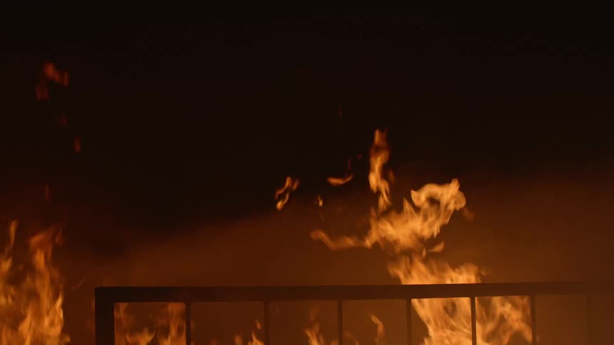 Flame billows in the night near a metal hand rail