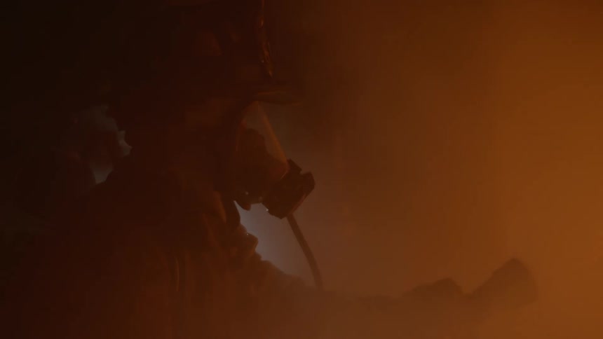 Two firefighters shining lights and spraying water in smoke filled room