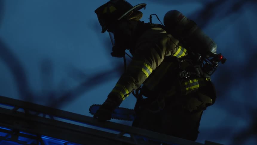 A firefighter climbs a ladder to reach a building