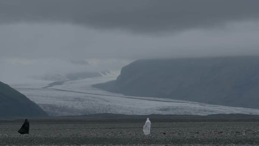 Two people wearing robes are standing on a field on a foggy day