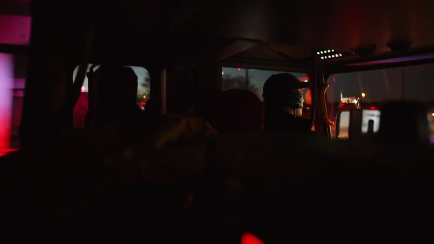 People are riding in a dark bus at sunset