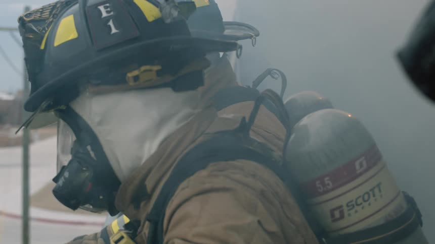 Firefighters stand in the smoke outside