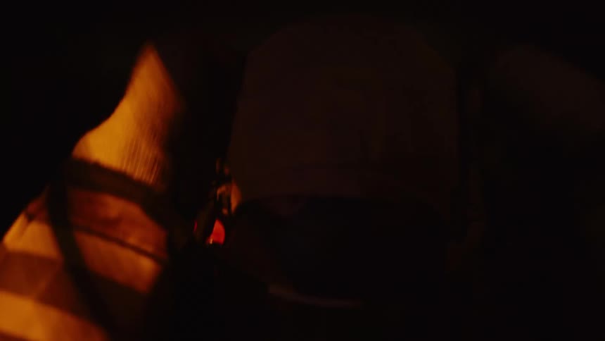 A firefighter wearing a mask removes a protective hood from their head